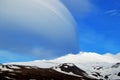 Snowy volcanic mountain in a sunny day and interesting shaped clouds