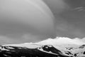 Snowy volcanic mountain in a sunny day and interesting shaped clouds in black and white