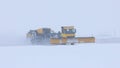 Snowy winter at the airport and a big snowplow removes snow