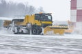 Snowy winter at the airport and snowplow removes snow from the runway