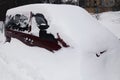 Snowy winter in a big city. A car covered in a huge snowdrift. Abnormal weather in winter. Snowfall and New Year Royalty Free Stock Photo