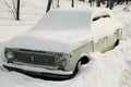 Snowy winter in a big city. Old car that covered in a huge snowdrift. Abnormal weather in winter. Snowfall and New Year Royalty Free Stock Photo