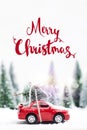 Snowy Winter Forest with miniature red car carrying a christmas Royalty Free Stock Photo