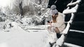 snowy winter fun. cutie girl, dressed in warm winter clothes, fully covered with snowflakes, is sitting on bench and