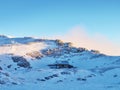 Snowy winter mountain and old stony cottage in small valley bellow peak. Clear blue sky. Royalty Free Stock Photo