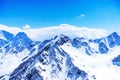 Snowy winter mountains and clear blue sky and clouds on a sunny day. Caucasus Mountains, Russia, view from the ski resort of Elbru Royalty Free Stock Photo