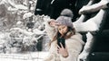 snowy winter selfie. cutie girl, dressed in warm winter clothes, fully covered with snowflakes, is sitting on bench and