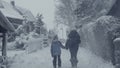 Snowy winter street of mountain town with walking woman, village snow calamity.