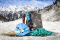 Snowy winter. A wooden board with a grey backpack, a blue helmet and a turquoise rope with blurred mountain background.