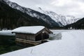 A snowy wooden hut on the shore of a lake in the Alps. Royalty Free Stock Photo