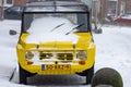 Snowy yellow Citroen Mehari car parked in winter scene street