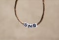 `SNS` alphabet white cube in a round rope.