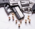 A snub nosed, stainless 357 magnum revolver on top of a black 9mm pistol with several bullets for each caliber in front of them Royalty Free Stock Photo