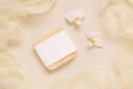 Soap bar near white orchid flowers on light yellow top view. Mockup. Skincare product