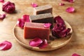 Soap bars with rose petals on wooden table