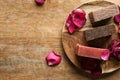 Soap bars with rose petals on wooden table