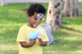 Soap bubble in blued green background, happy African boy making bubbles with blowing bubble gun toy in garden. Kid spends time Royalty Free Stock Photo