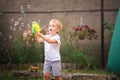 Soap Bubble Games. The boy in the backyard is playing with a water gun. Boy in summer playing with water and soap bubbles close-up Royalty Free Stock Photo