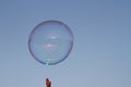 a soap bubble rises in the blue sky and tries to be apprehended with the fingertips of one hand Royalty Free Stock Photo