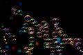 Soap bubbles from the bubble blower in dark or black background. Royalty Free Stock Photo
