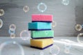 Soap bubbles with stack of colored sponges for washing dishes against grey background Royalty Free Stock Photo