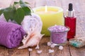 Soap, burning candle, bowl with sea salt, bottle with aromatic oil, lilac flowers and towels on wooden background Royalty Free Stock Photo