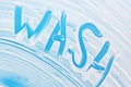 Soap foam on blue background with handwritten word wash. Cleanliness, hygiene, sanitation, disinfection concept