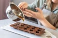 Soap maker a woman pours hot organic cocoa butter with aromatic oils into molds for making cosmetics for body skin care Royalty Free Stock Photo