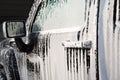 Soap touchless foam on the side glass and door of a black car at a self-service car wash Royalty Free Stock Photo