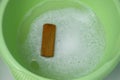 Soapy water in a basin with a brush prepared for hand washing clothes.