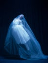 Young graceful balerina in image of ghost bride in art performance isolated on dark background in neon light.