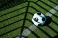 Soccer ball black and white on artificial ground ground with shadows stripes, on the line Royalty Free Stock Photo