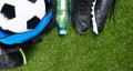 Soccer ball in a blue bag, boots, a bottle of water and a sporty T-shirt, against the background of grass Royalty Free Stock Photo