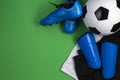 Soccer ball, blue boots, cleats, white t-shirt and black shorts on green background. Flat lay, top view Royalty Free Stock Photo