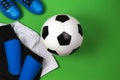 Soccer ball, blue boots, cleats, white t-shirt and black shorts on green background. Flat lay, top view Royalty Free Stock Photo
