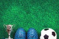 Soccer ball, a cup and cleats against green artificial turf Royalty Free Stock Photo