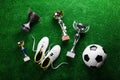 Soccer ball, cleats and trophies against green artificial turf Royalty Free Stock Photo