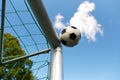 Soccer ball flying into football goal net over sky Royalty Free Stock Photo