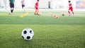 Soccer ball on green artificial turf with blurry kid soccer team training Royalty Free Stock Photo