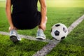 Soccer ball on green artificial turf with footballer is sitting and catch the ankle Royalty Free Stock Photo