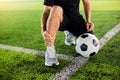Soccer ball on green artificial turf with footballer is sitting and catch the ankle Royalty Free Stock Photo