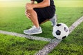 Soccer ball on green artificial turf with footballer is sitting and catch the knee Royalty Free Stock Photo