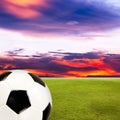 Soccer ball with green grass field against sunset sky Royalty Free Stock Photo