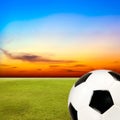 Soccer ball with green grass field against sunset sky Royalty Free Stock Photo