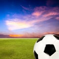 Soccer ball with green grass field against sunset sky Royalty Free Stock Photo