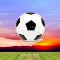 Soccer ball in hand with soccer field and sunset sky Royalty Free Stock Photo