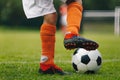 Soccer ball kick. Close up of legs and feet of football player in red socks and cleats running and dribbling with the ball Royalty Free Stock Photo