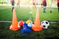 Soccer ball and marker cone with training equipment on green artificial turf with blurry player training background. Royalty Free Stock Photo