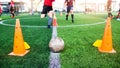 Soccer ball and marker cone with training equipment on green artificial turf with blurry player training background. Royalty Free Stock Photo