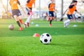Soccer ball and marker cones on green artificial turf with blurry soccer team training Royalty Free Stock Photo